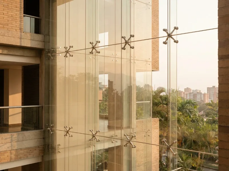 Fachada flotante de vidrio con arañas de acero en edificio residencial